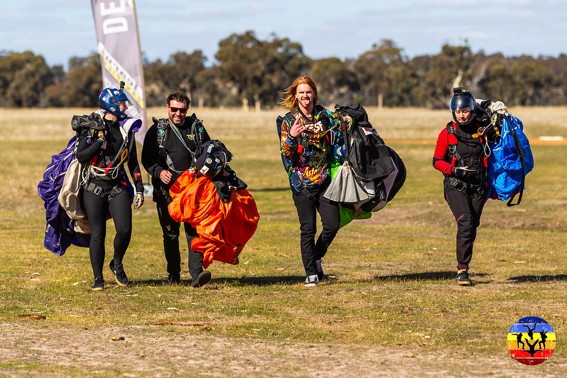 Four skydiver are happy after landing in field