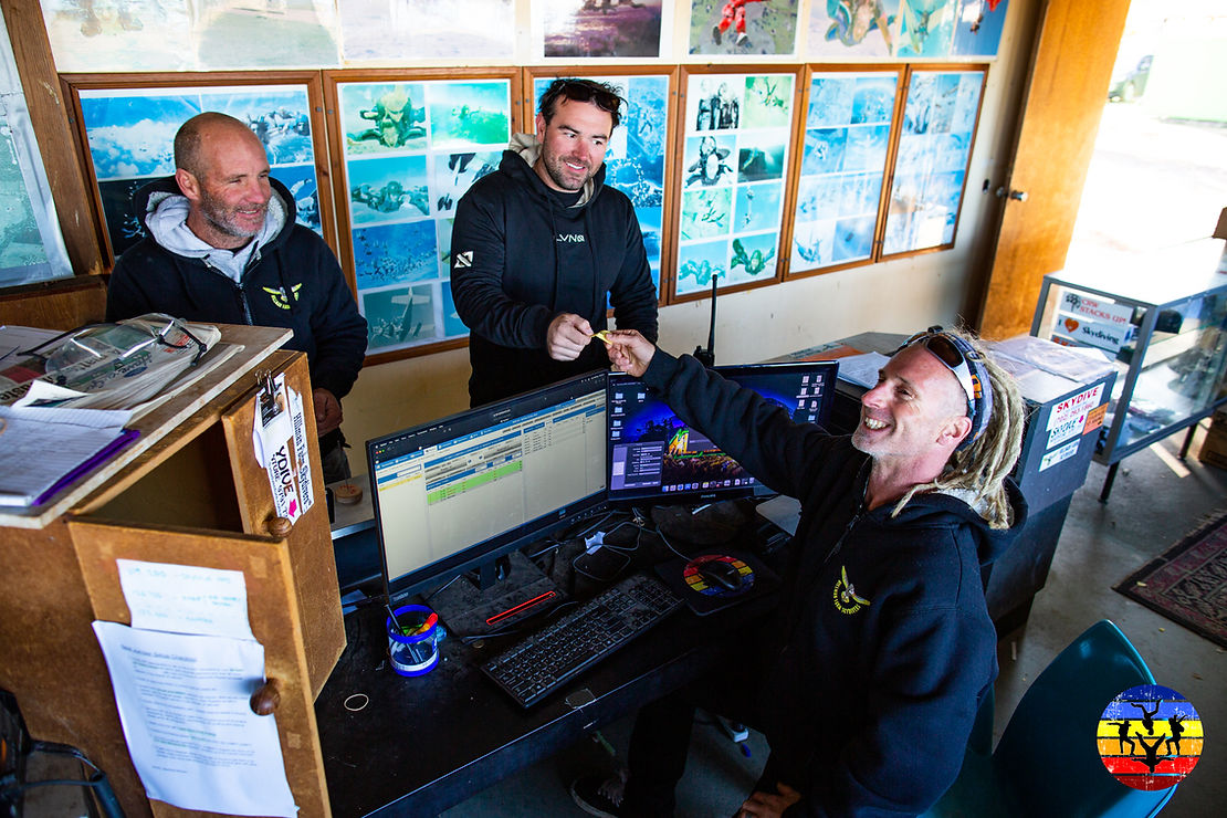 three males at skydive school desk