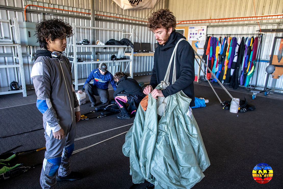 Skydivers learning to pack a parachute in hangar