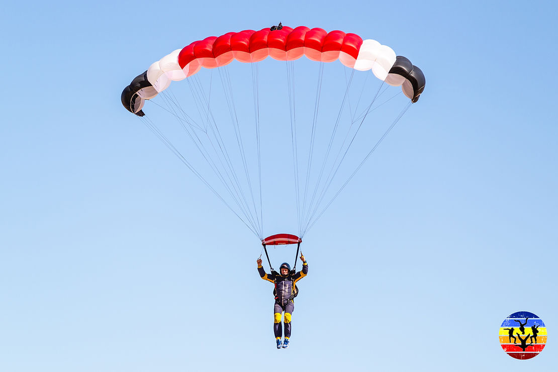 Man under black, white and red parachute