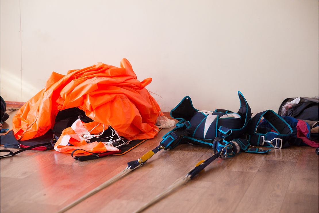 orange parachute laying on ground beside a blue container