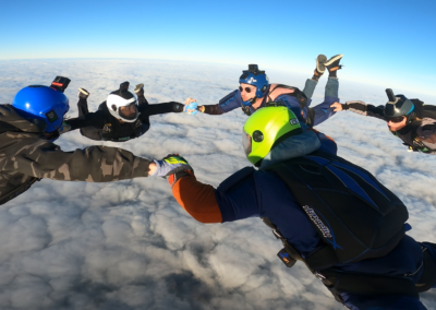 Five skydivers in a star formation during freefall over a some cloud in Western Australia.