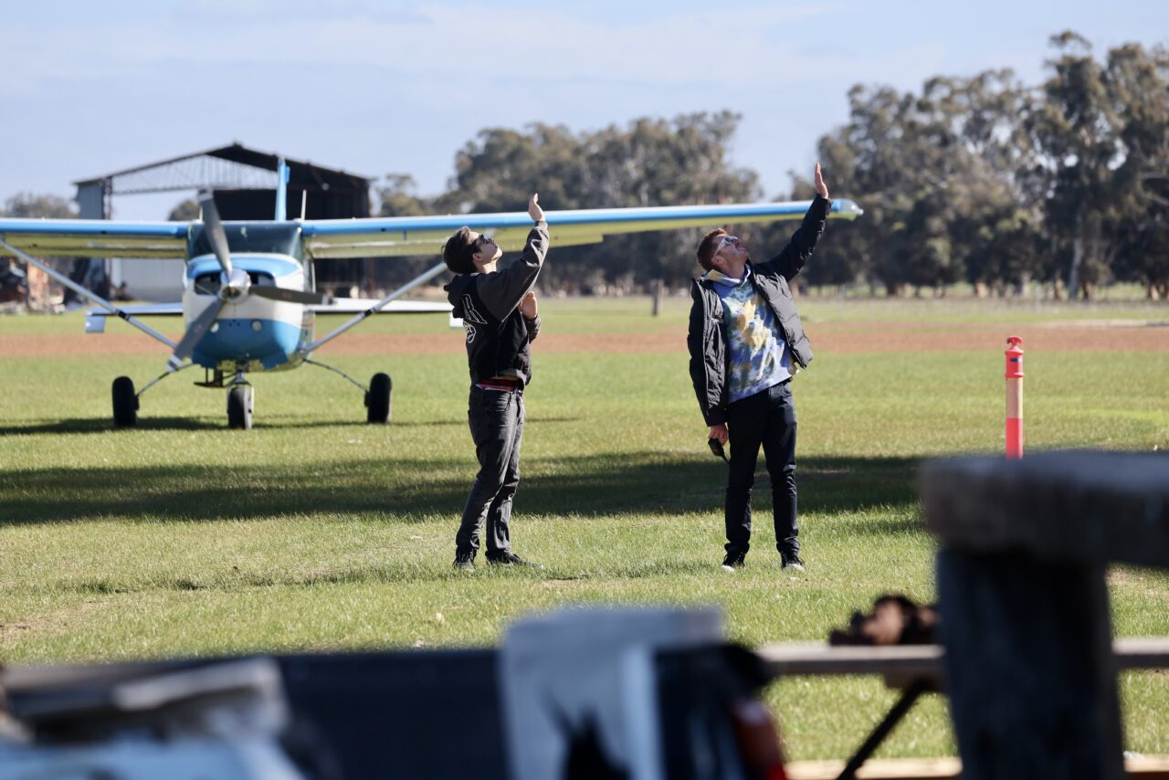 Skydivers and ground crew beside the jump plane on the grass airstrip at Hillman Farm