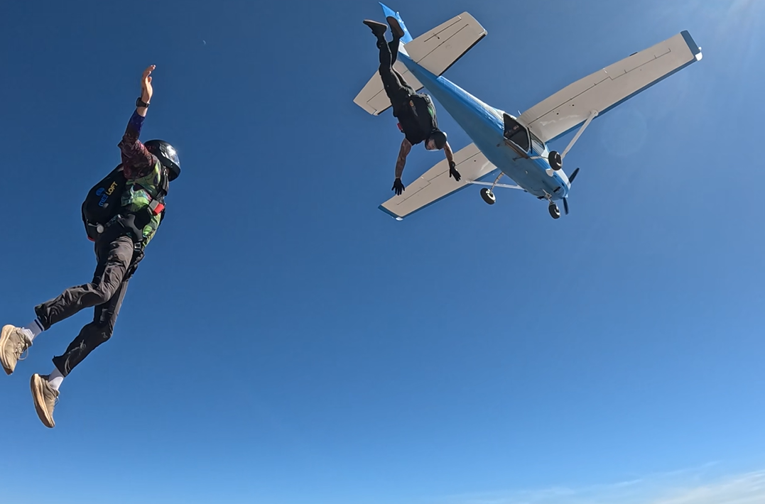 Skydivers leaving a blue aircraft in a clear sky above Hillman Farm