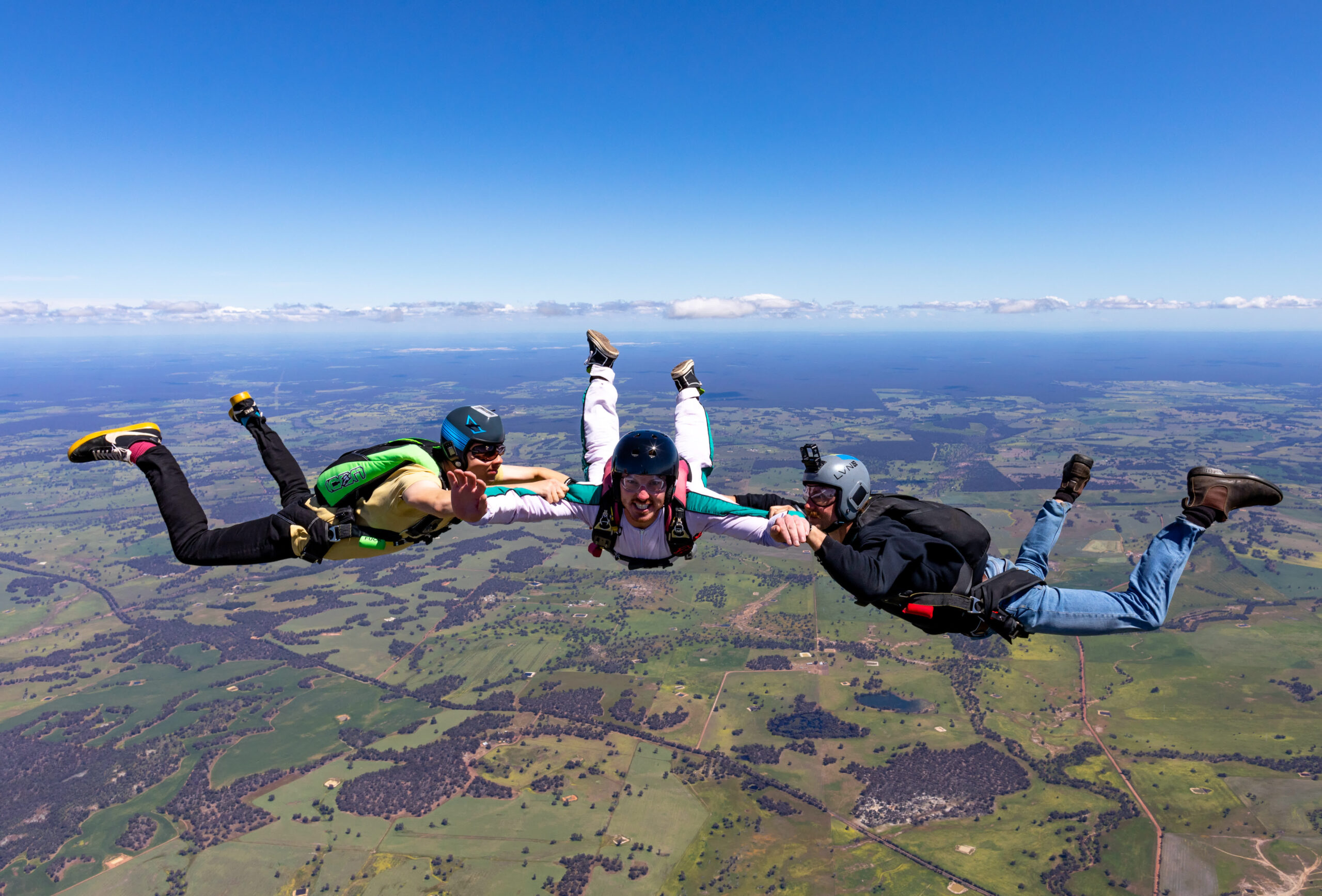 Skydiving Licence Cost in WA: The Honest Breakdown 3 An AFF student in freefall with two instructors beside her over the farmland near Darkan, WA